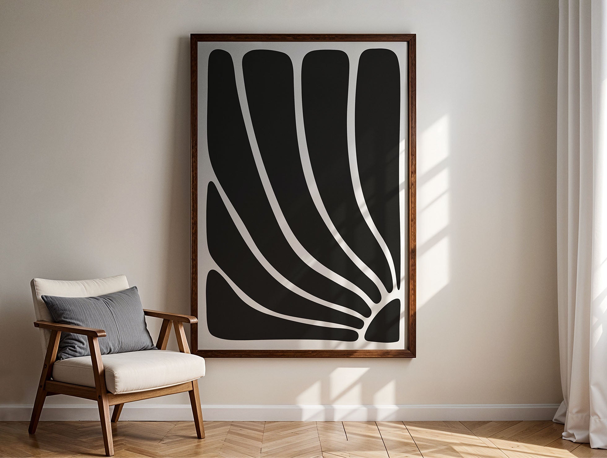 Large abstract black and white flow wood framed art print hanging in living room on a white wall with shadows next to wooden chair.