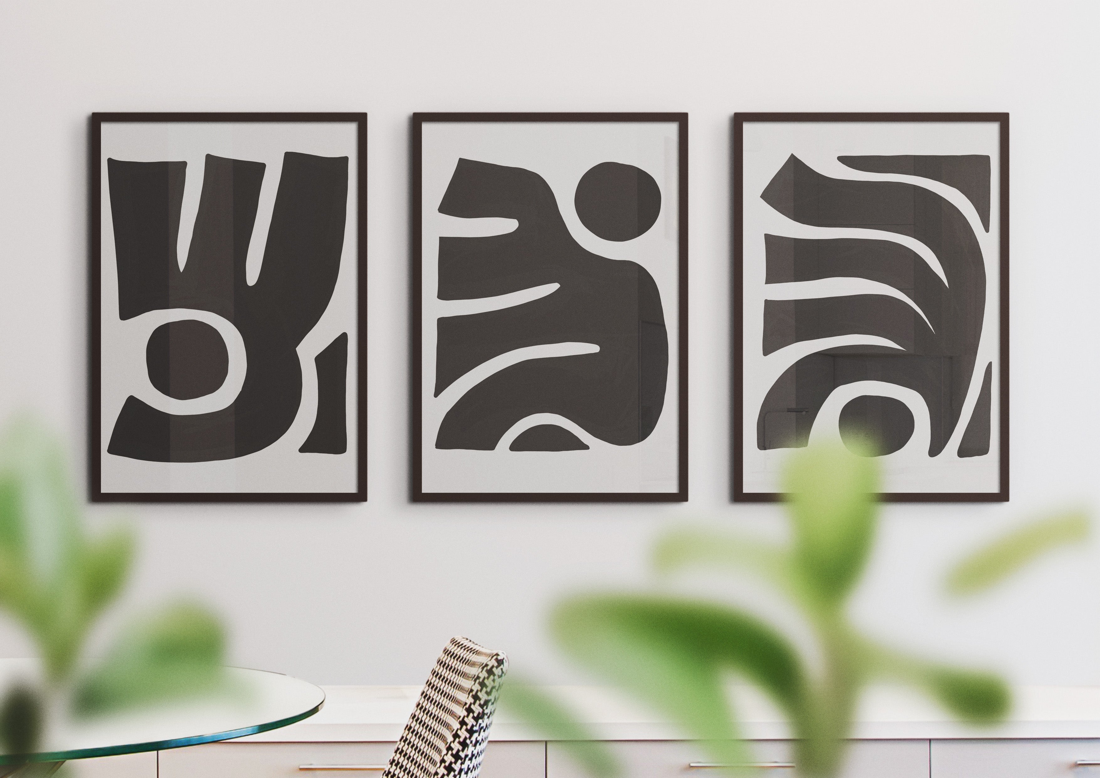 Besma Triptych modern abstract art prints – museum-quality framed wall art for elegant interiors. Shown as a triptych in black frames hanging on white wall in front of greenery.