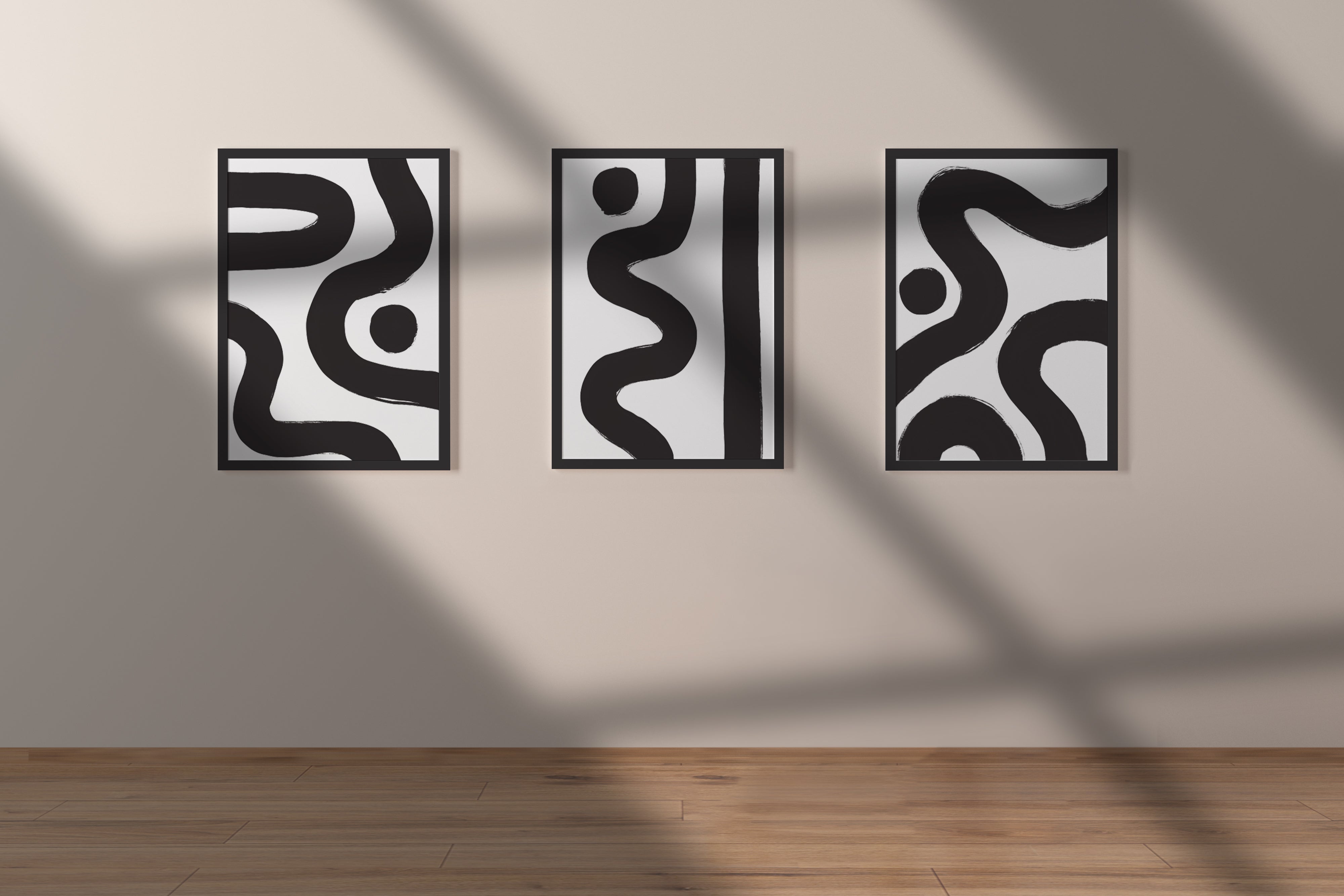 Ebb & Line luxury modern abstract art print – museum-quality black and white triptych for contemporary interiors. Shown as a three prints on black frames against a light beige wall with shadows cast across it.